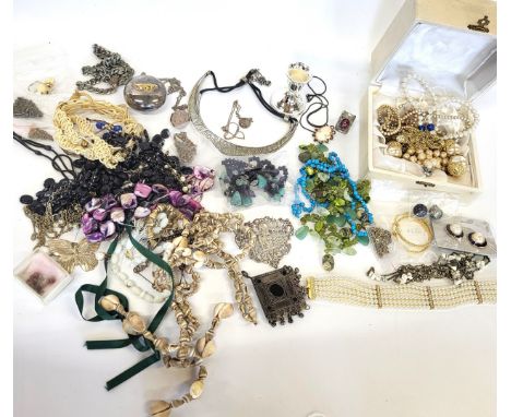 A bag of costume jewellery including a short candlestick, necklaces, buckles, pill boxes, cameo brooch, and rings.