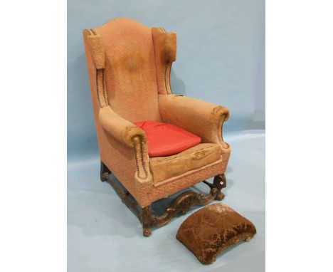 A continental stained wood wing armchair of carved front supports and H-stretcher and a gilt wood foot stool, both in need of