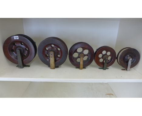 Five vintage wooden fishing reels ranging in size from 23.5cm diameter to 16.5cm diameter