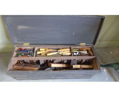 A collection of woodworking tools to include chisels, moulding planes in a vintage carpenters tool chest