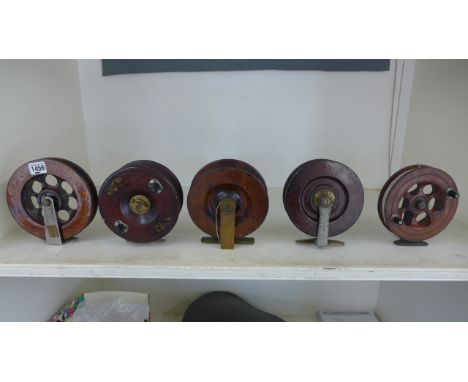 Five vintage wooden fishing reels ranging in size from 16cm diameter to 15cm diameter