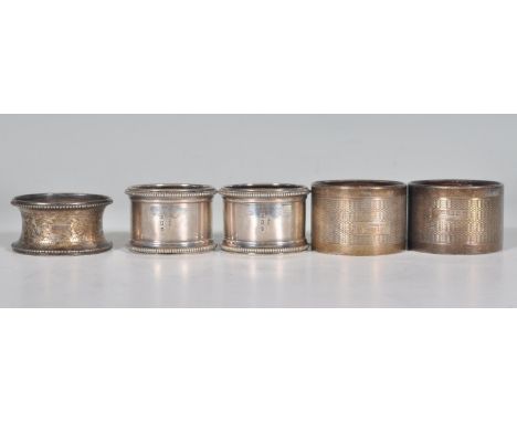 A group of five silver hallmarked napkin rings to include a pair of cylindrical form rings with beaded borders (hallmarked Bi
