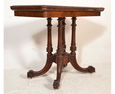 A VIctorian 19th century walnut Aesthetic movement card / games table being raised on a quatrefoil base with 4 columns having