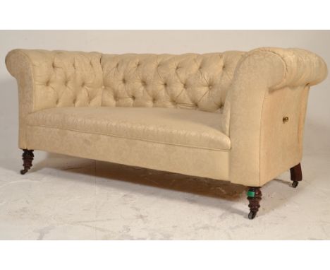 A Victorian 19th century mahogany Chesterfield drop arm sofa - settee. Raised on castors with turned legs having a cream upho