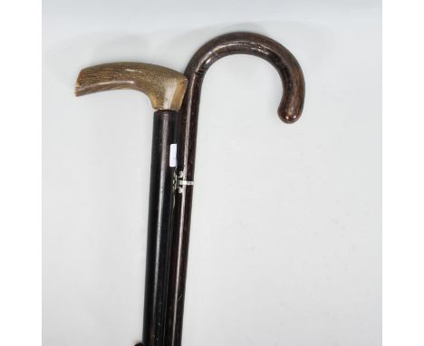 A pair of 20th Century walking sticks to include an ebonised shaft having a crook horn handle, a dark wood stick having a pie