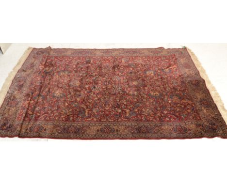 A 20th Century Persian Islamic floor rug / carpet having a central red ground panel with floral design with blue and cream fl