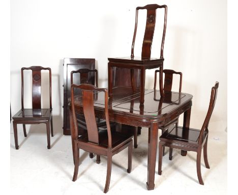 A large 20th century Chinese mahogany dining table and chairs suite. The large table with carved and detailed frieze being ra