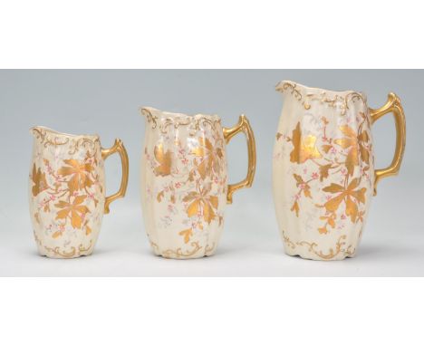 A set of three vintage early 20th Century jugs of graduating sizes having shaped gilt handles with moulded tapering bodys and