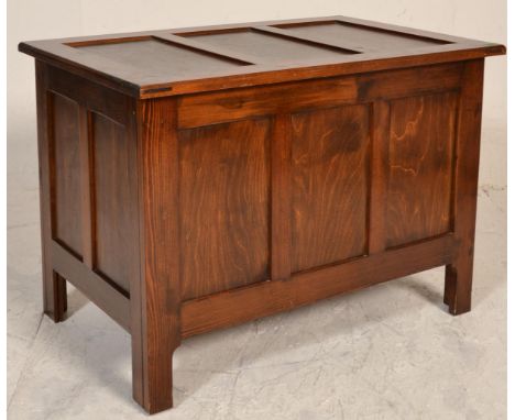 A 20th century antique style oak coffer raised on squared legs with fielded panel body and sides having hinged top opening to