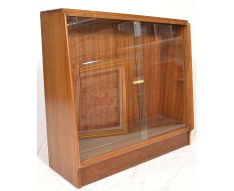 A retro 20th century G-Plan teak wood library bookcase cabinet being raised on a plinth base with twin sliding glass doors an