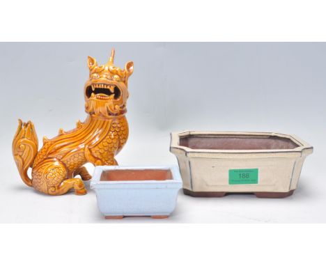 A Chinese ceramic figure of a Qilin / mythical beast modelled sitting having an orange glaze together with two Chinese small 