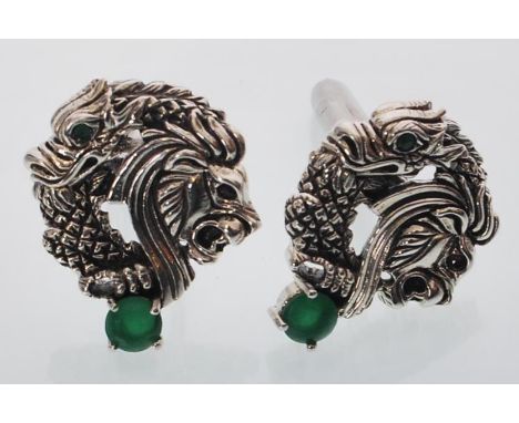 A pair of sterling silver cufflinks decorated with dragon and lions heads inset with jade style stones. Gross weight 13.3 gra