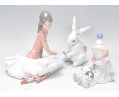 A group of three Lladro ceramic figures to include a young clown boy sitting down with a puppy on his legs, seated ballerina 