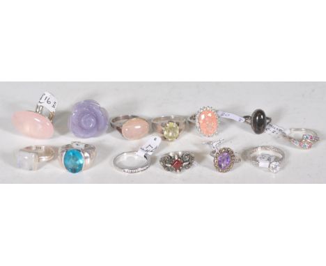 A selection of thirteen silver rings to include a white stone solitaire ring, a purple stone panel ring set with marcasites, 