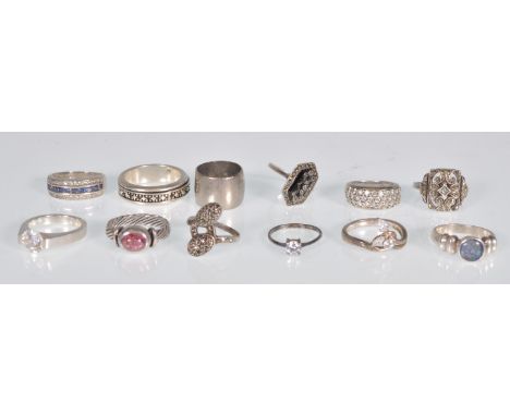 A group of 12 silver rings to include an Art Deco panel ring set with marcasites, a twist design shank with an oval cut pink 