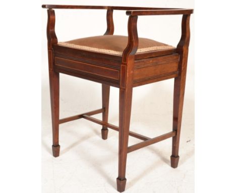 An Edwardian mahogany inlaid piano stool seat being raised on tapering legs with hinged seat having a railed and inlaid back 