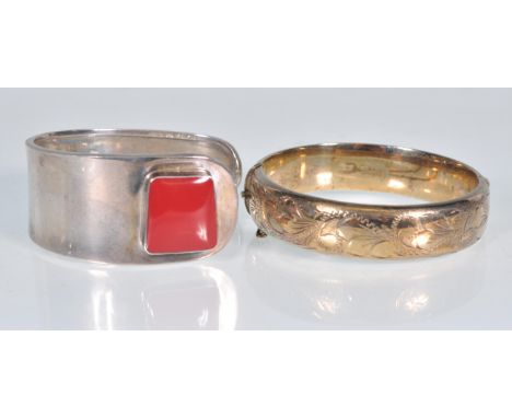 Two silver bangles to include an English hallmarked bangle with a hinge opening and engraved decoration together with a stamp