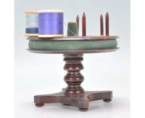 A 19th Century Victorian mahogany bobbin stand having a rotating round top with stands to each, having a central thimble stan