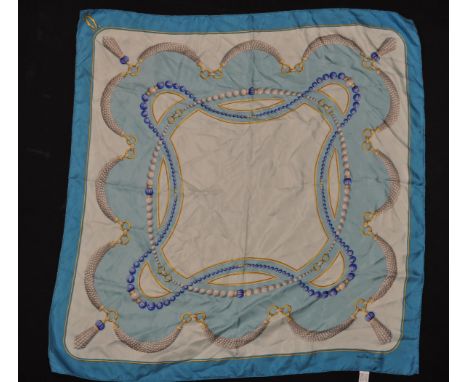 A vintage ladies Must De Cartier silk scarf having a blue ground with a pearl necklace themed design. Marked must de Cartier 
