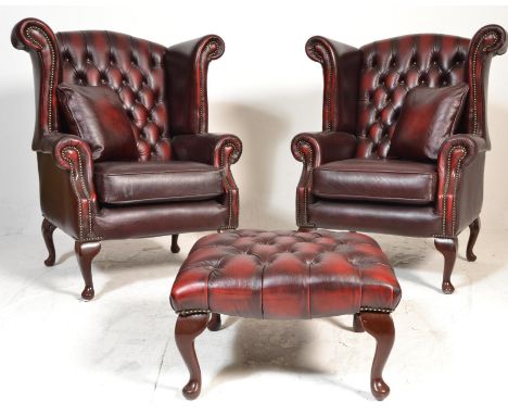 A pair of 20th Century Antique style red oxblood  leather Chesterfield button back wing armchairs being raised on cabriole le