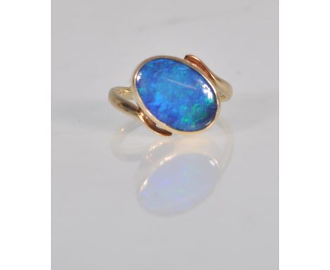 A stunning 9ct yellow gold and black opal ladies dress ring set with an oval cut black opal cabochon and having curved should