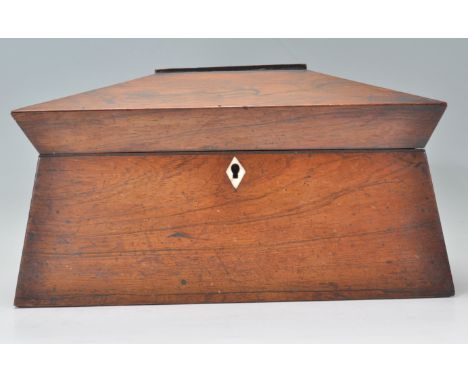 A 19th Century Georgian mahogany tea caddy of sarcophagus form having an ivory key escutcheon. The hinged lid opening to reve