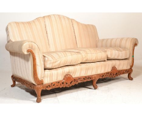 A large 20th century antique style camel back sofa settee being raised on squared legs with pierced frieze having overstuffed