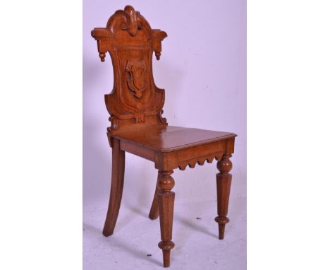 A Victorian carved oak 19th century armorial hall chair. Raised on ring turned legs with panel seat beneath carved back rest 