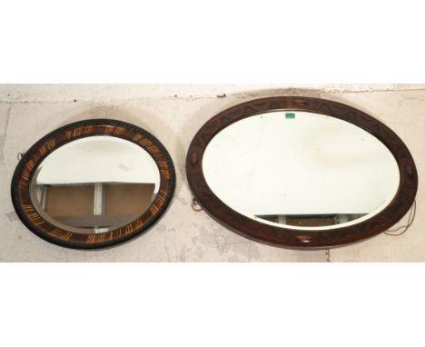 A vintage 20th Century oval oak framed mirror with carved decoration a single beveled edge mirrored panel. Together with an E