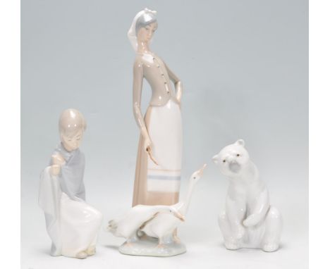 A group of three Lladro&nbsp;ceramic figurines to include a polar bear, a figure of a young boy and lady with two geese raise