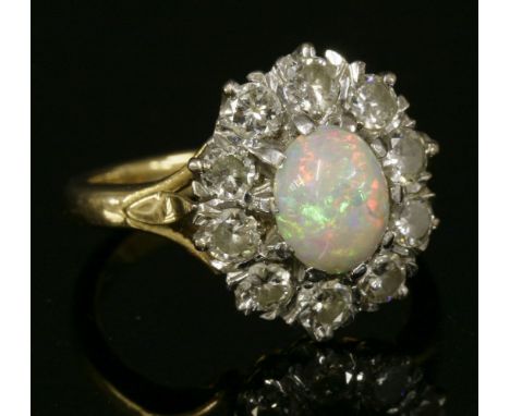 An opal and diamond cluster ring, with an oval cabochon opal claw set to the centre, surrounded by a row of brilliant cut dia