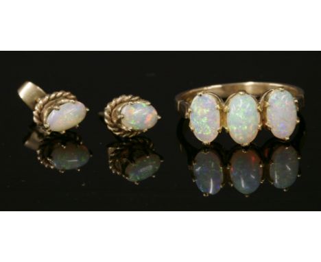 A gold three stone opal ring,composed of three oval cabochon opals, all claw set to scalloped collets with later underbezel a