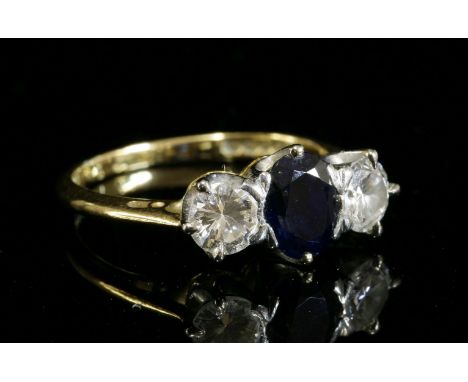 An 18ct gold three stone sapphire and diamond ring,with an oval mixed cut sapphire, claw set to a white collet.  A brilliant 