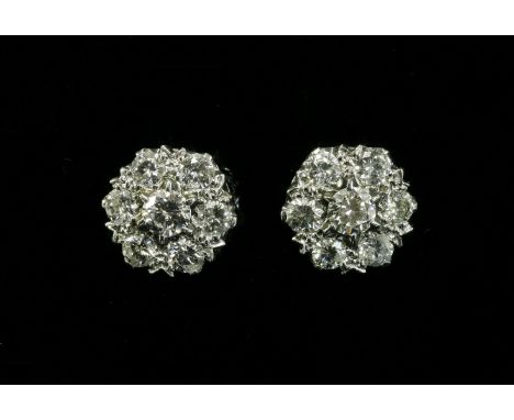 A pair of white gold, seven stone diamond cluster earrings, with a brilliant cut diamond, claw set to the centre, surrounded 