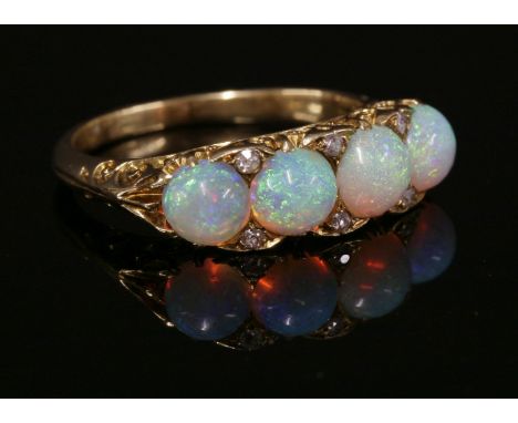 A four stone opal and diamond carved head ring, c.1910,four circular cabochon opals, all claw set to a carved head with pairs