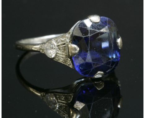 An Art Deco single stone sapphire ring with diamond set shoulders,a cushion-shaped, mixed cut, parti-coloured sapphire, four 