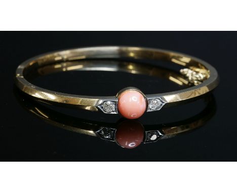 An Edwardian coral and diamond set hinged gold bangle, c.1910,an 8mm bouton coral bead, peg set to the centre of the top half