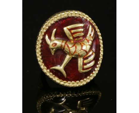 An Italian gold and enamel circular plaque ring,depicting a falcon, with the repoussé bird to a burgundy enamel ground.  A tw