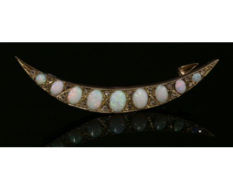 An Edwardian opal and diamond crescent brooch, c.1910,with a curved row of graduated oval cabochon opals.  The opals all grai