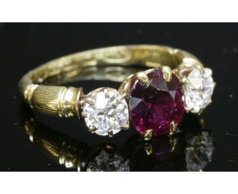 An 18ct gold Edwardian three stone ruby and diamond ring, with a circular mixed cut ruby,claw set to the centre.  An old Euro