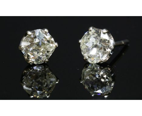 A pair of single stone diamond stud earrings,with two old cushion cut diamonds, claw set to white collets with post fittings,