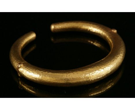 A gold, graduated, hollow, round section torque bangle,by Ilias Lalaounis, with two hinged sections to the lower half with a 