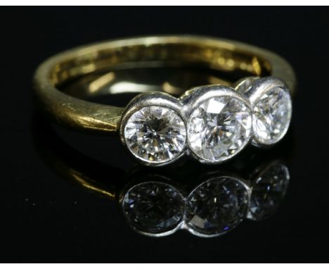 An 18ct two colour gold three stone diamond ring,with three graduated brilliant cut diamonds rub set in white to yellow under