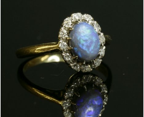 A black opal and diamond oval cluster ring, c.1950,with an oval cabochon black opal, claw set to the centre, surrounded by ei