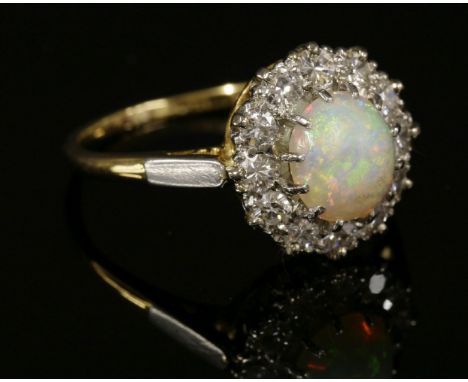 A two-colour gold, opal and diamond cluster ring,with a circular cabochon opal, claw set to the centre.  A border of brillian