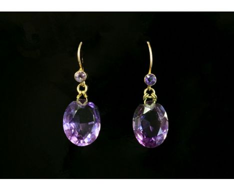 A pair of Edwardian amethyst drop earrings,with a circular mixed cut amethyst, rub set in a plain collet to hook fittings.  E