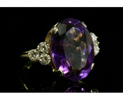 An 18ct gold amethyst and diamond ring, c.1980,with an oval mixed cut amethyst, four claw set to a plain collet, a trefoil cl