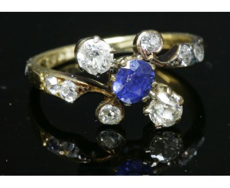 An Art Nouveau sapphire and diamond crossover ring with an oval mixed cut sapphire,claw set to the centre.  An old European c