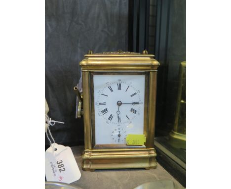 An Edwardian brass carriage clock, with bevelled glass, the enamel dial with subsidiary alarm dial, the twin train movement w