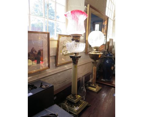 A late Victorian brass and onyx oil lamp, of column form with square open base, red glass shade, 83.5 cm high, converted for 